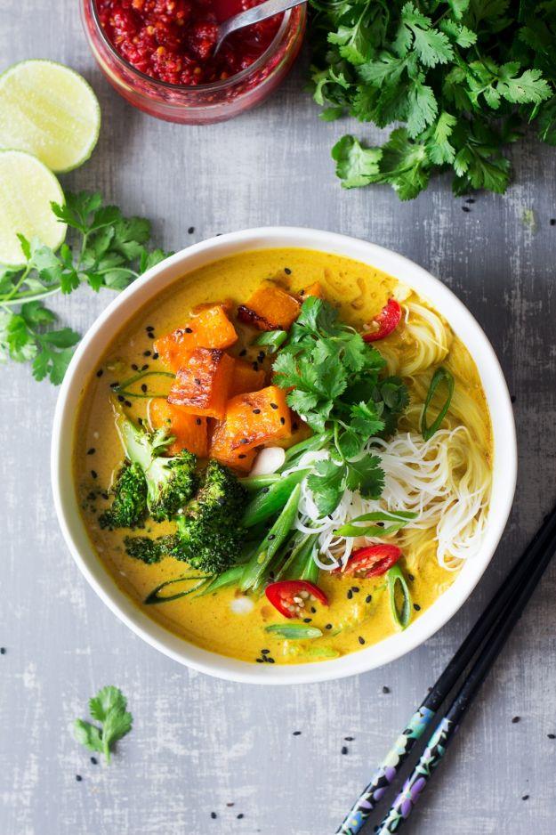 Vegan khao soi soup in a white bowl with butternut squash, broccoli, thin noodles, red chili and cilantro