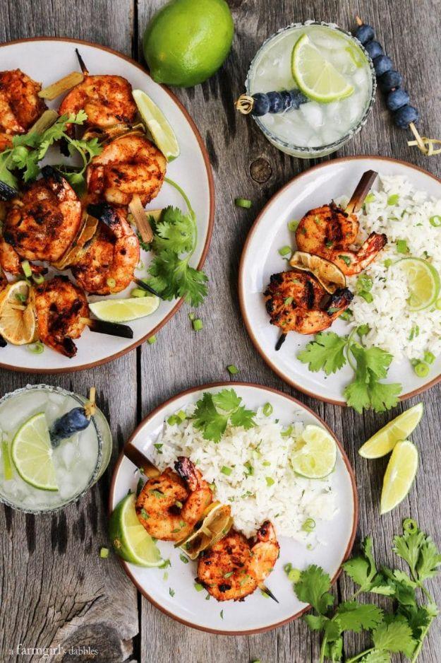 Grilled margarita shrimp kebabs on skewers with lime slices, served on plates with rice and margarita glasses