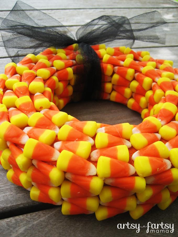 Candy corn wreath with alternating orange, yellow and white rows, a black tulle bow and Artsy-Fartsy Mama watermark