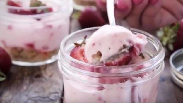 DIY mason jar cheesecake, pink strawberry cheesecake layered over pecan shortbread crumbs in small glass jars
