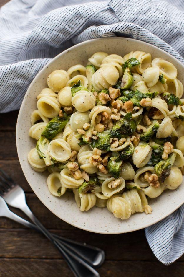 Brussels sprout pasta in lemon cream sauce topped with toasted walnuts and black pepper in a shallow bowl
