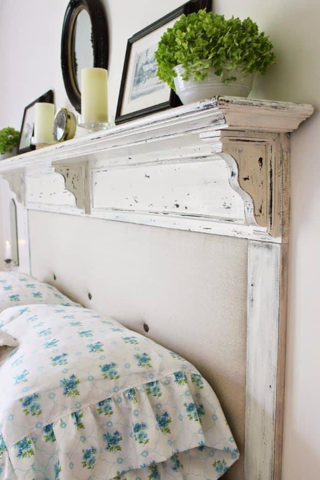 Converted shelf headboard, a white distressed mantel shelf above a cream upholstered panel and blue floral bedding