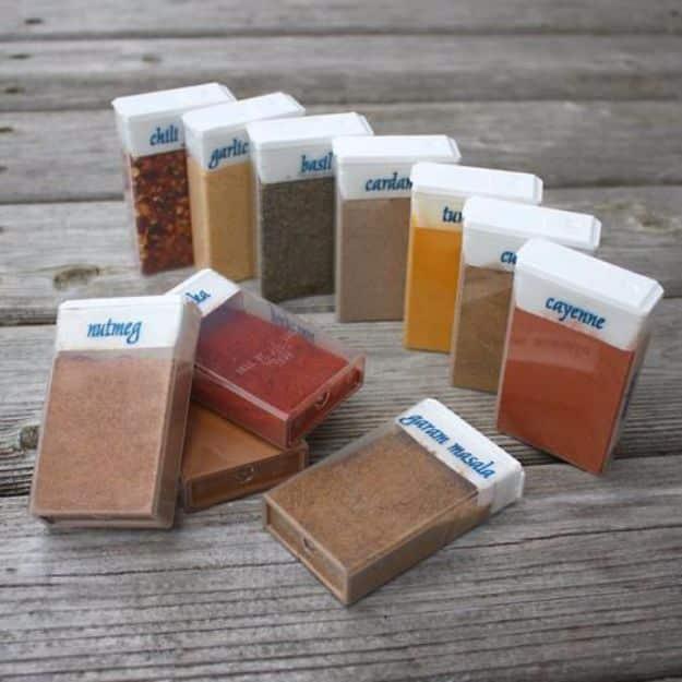 Flat TicTac boxes filled with labeled ground spices in reds and browns, laid out on a weathered wood table