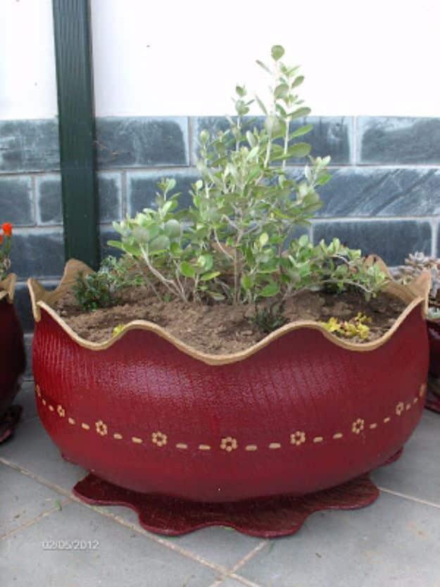 Burgundy painted tire flower pot turned inside out with a scalloped cream rim and painted flowers on the side