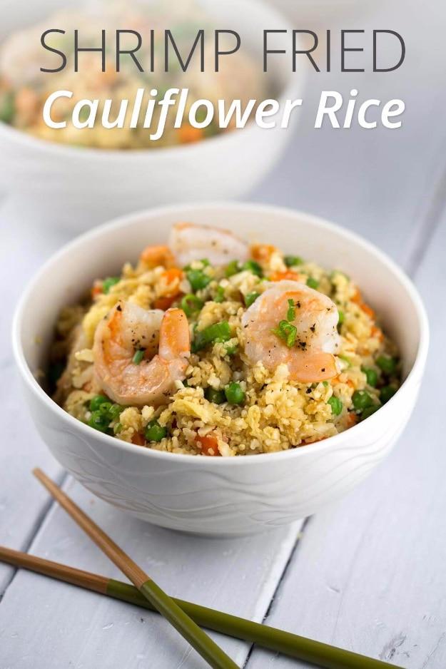 Shrimp fried cauliflower rice bowl with carrots, peas and scrambled egg cooked in a wok for a low carb one pan dinner