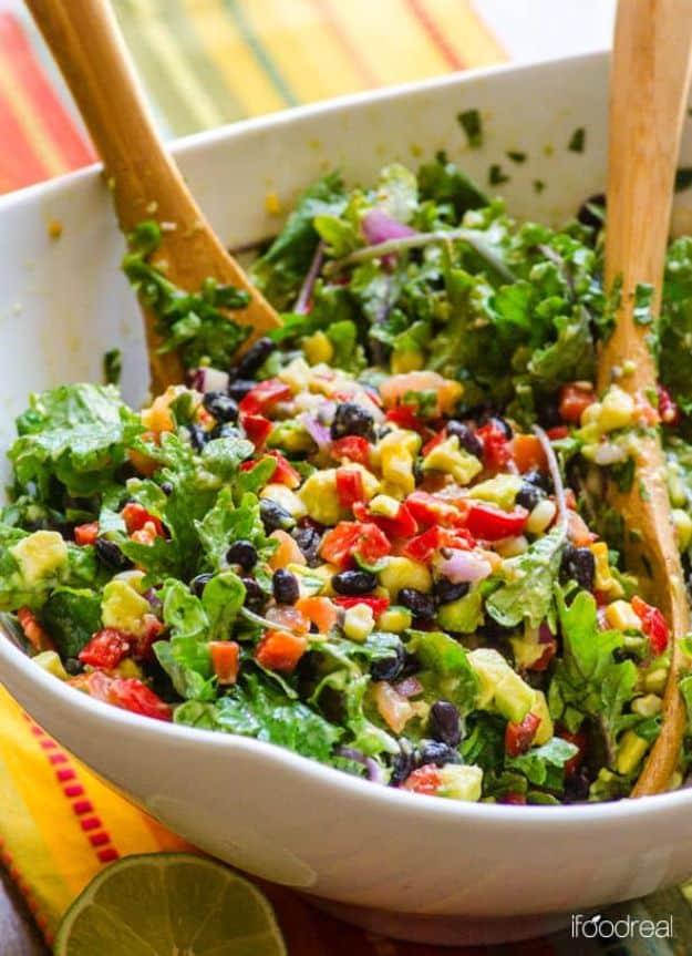 Mexican kale salad with black beans, corn, red pepper and avocado tossed in a large white serving bowl