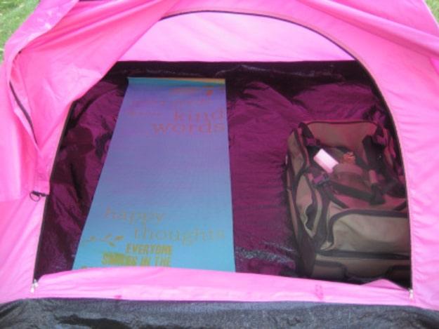 Yoga mat as a camping sleeping pad, a printed teal mat laid flat inside a bright pink tent beside a pack