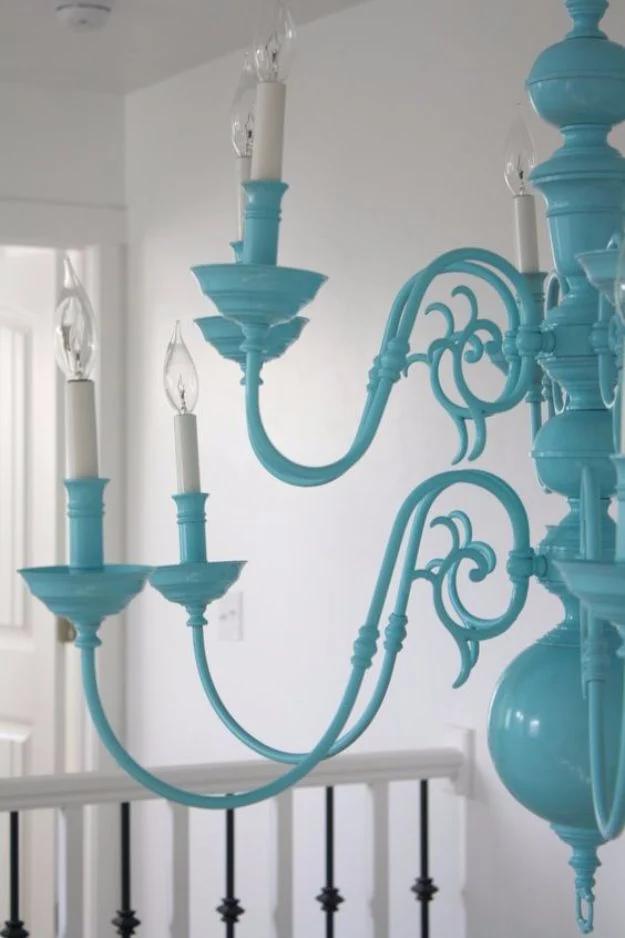 Ornate chandelier refinished in bright turquoise with white candle sleeves and a large round finial at the base