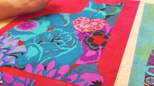DIY cat quilt in progress, a cat shape cut from teal and magenta floral fabric laid on red with a patterned heart