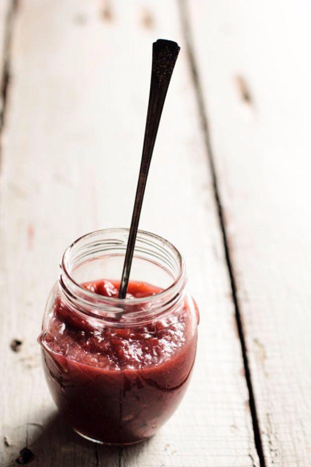 Rhubarb vanilla bean jam in a jar, pink and flecked with vanilla seeds, with fresh rhubarb stalks alongside