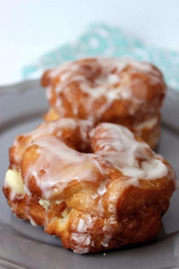 Easy cronuts made from crescent dough, fried golden and glazed, filled with vanilla pudding on a wire rack
