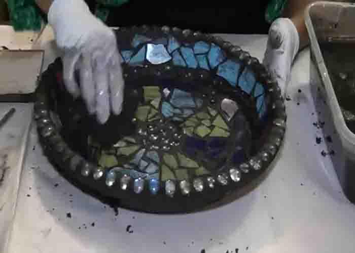Applying grout to the DIY mosaic bird bath