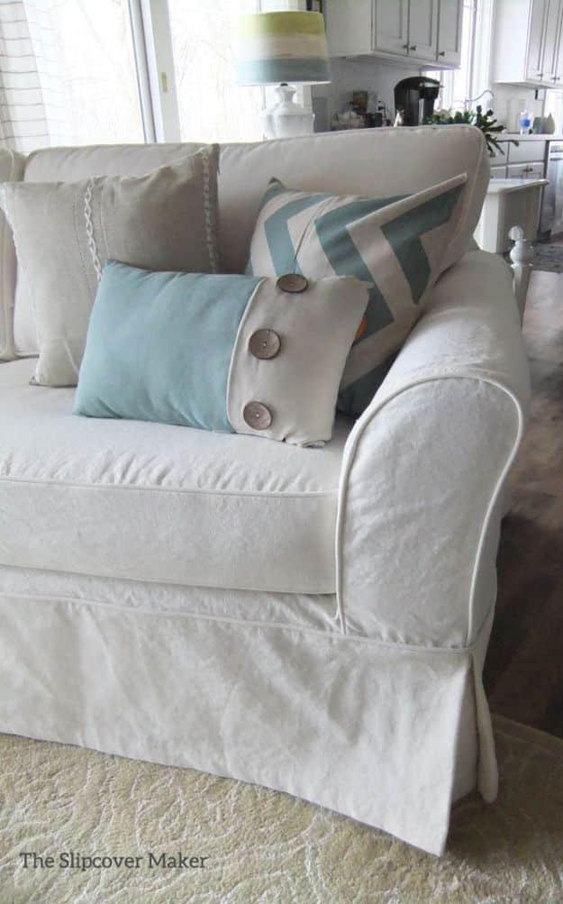 Sofa fitted with a creamy white cotton canvas slipcover with piped arms, styled with blue and plaid pillows