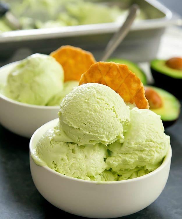 No churn avocado ice cream, pale green scoops in white bowls with a waffle crisp and half an avocado behind