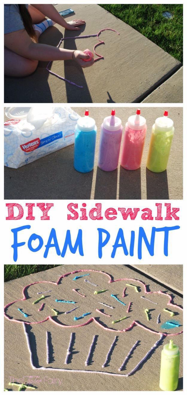 Four squeeze bottles of pink, blue, purple and yellow foam paint, with a large cupcake drawn in foam on a sidewalk