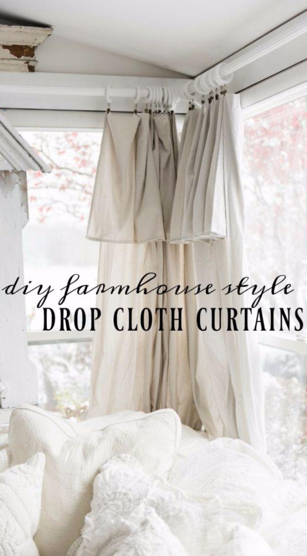 Neutral drop cloth curtain panels hang from metal rings at a window, the heavy fabric falling in soft folds