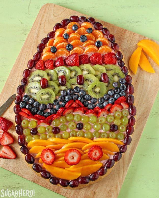 Easter fruit pizza shaped like a giant egg, banded rows of strawberries kiwi blueberries grapes and mango