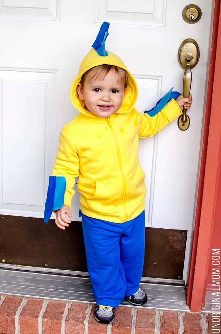 Child wearing a yellow hoodie Flounder costume with blue felt fins and stripes, blue pants and source watermark