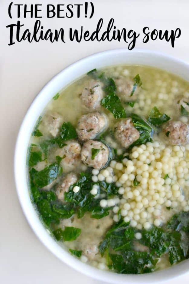 Italian wedding soup with small meatballs, pasta and greens floating in a clear broth in a white bowl