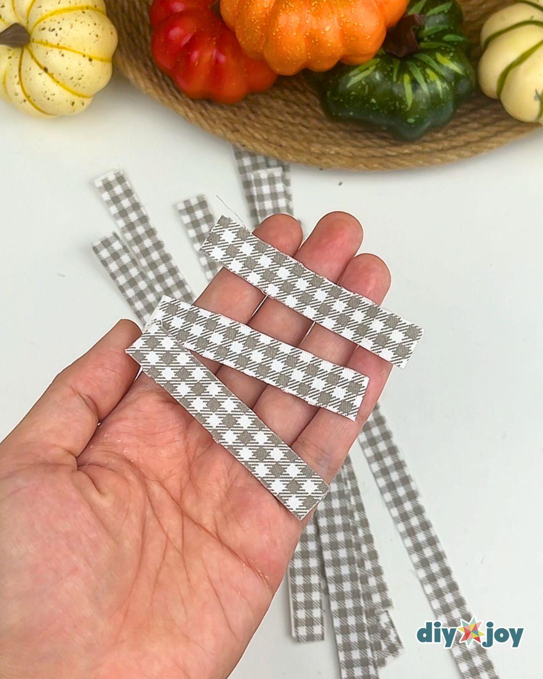 How To Make Fabric Tape - a hand holding gray gingham strips of several different widths cut to the pumpkin's curved height