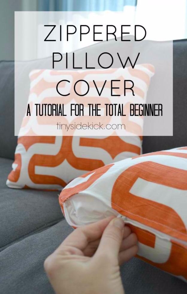 A gray zippered pillow cover in decor weight cotton on a sofa, its zipper closed along the bottom edge and the print showing.