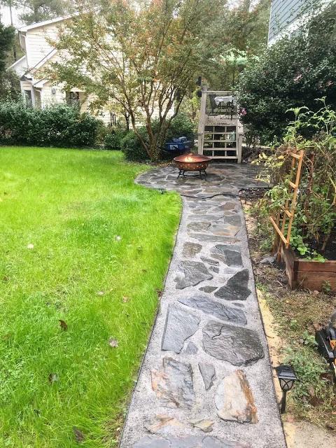 Natural slate walkway with irregular stones and packed joints curving across a lawn toward a fire pit