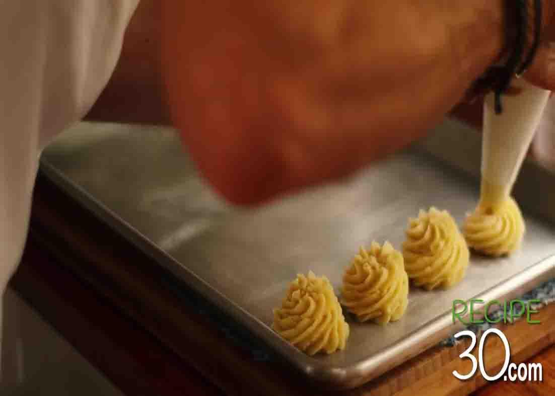 Piping the mashed potatoes onto the baking sheet