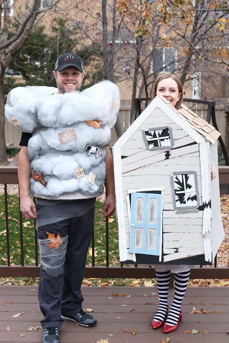 Two adults wearing a tornado costume and witch's house costume together outdoors for a handmade Wizard of Oz look