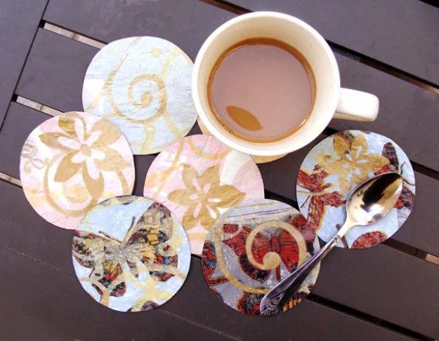 Seven round coasters cut from fused plastic bags in cream, blue and pink with gold swirls and butterfly print