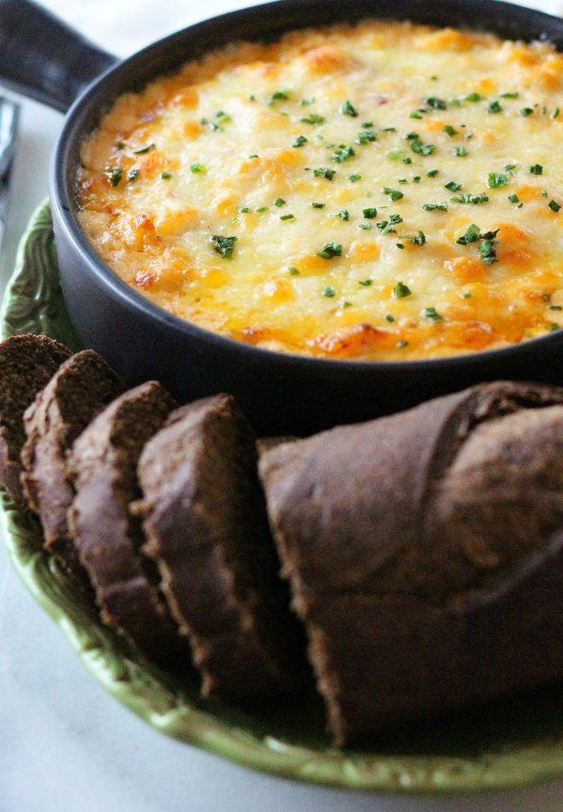 Reuben dip baked in a black skillet under browned melted cheese, with sliced dark rye bread beside it