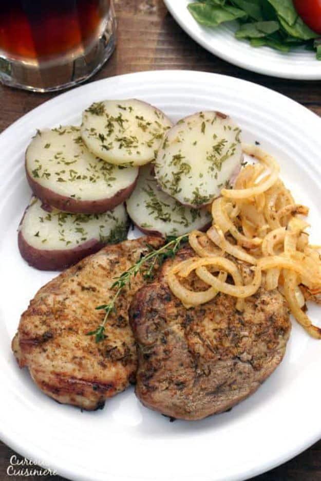 Grilled German schwenker chops served with sliced boiled potatoes and golden fried onions on a plate