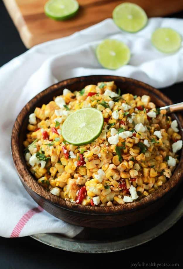 Grilled chili lime sweet corn salad with charred corn, queso fresco and cilantro in a dark wooden bowl