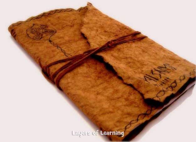 Medieval journal with a crumpled brown kraft paper cover tied shut with brown embroidery floss like an old book