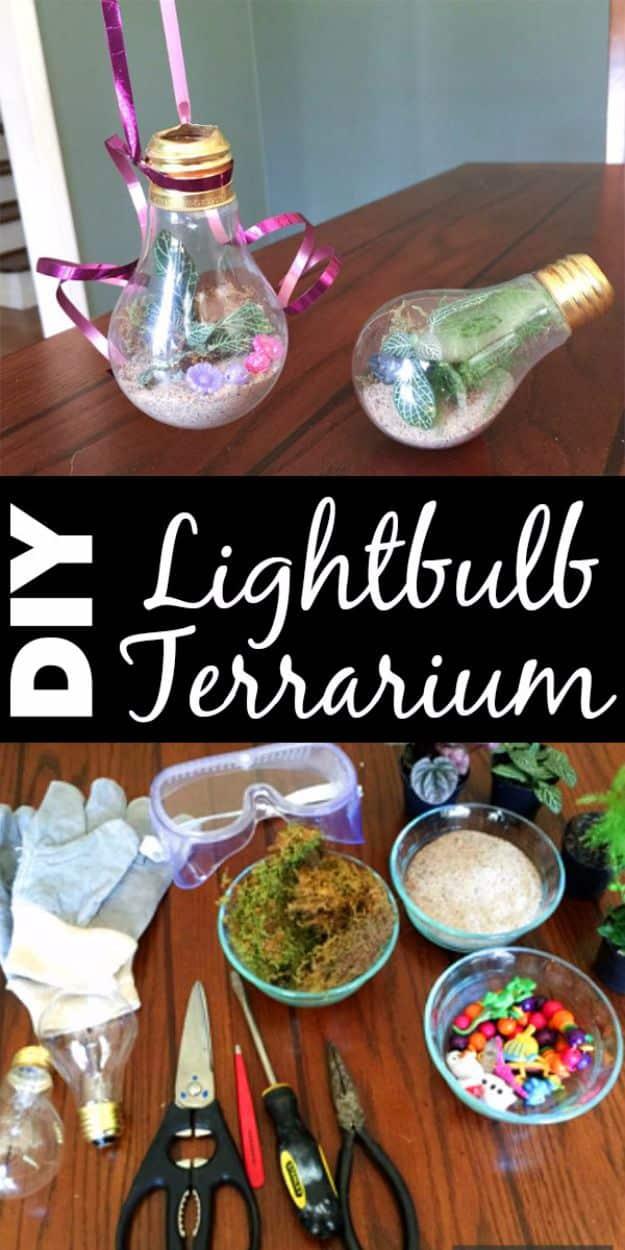 DIY lightbulb terrarium, two hollowed light bulbs of moss and air plants hung on ribbon beside tools and craft supplies