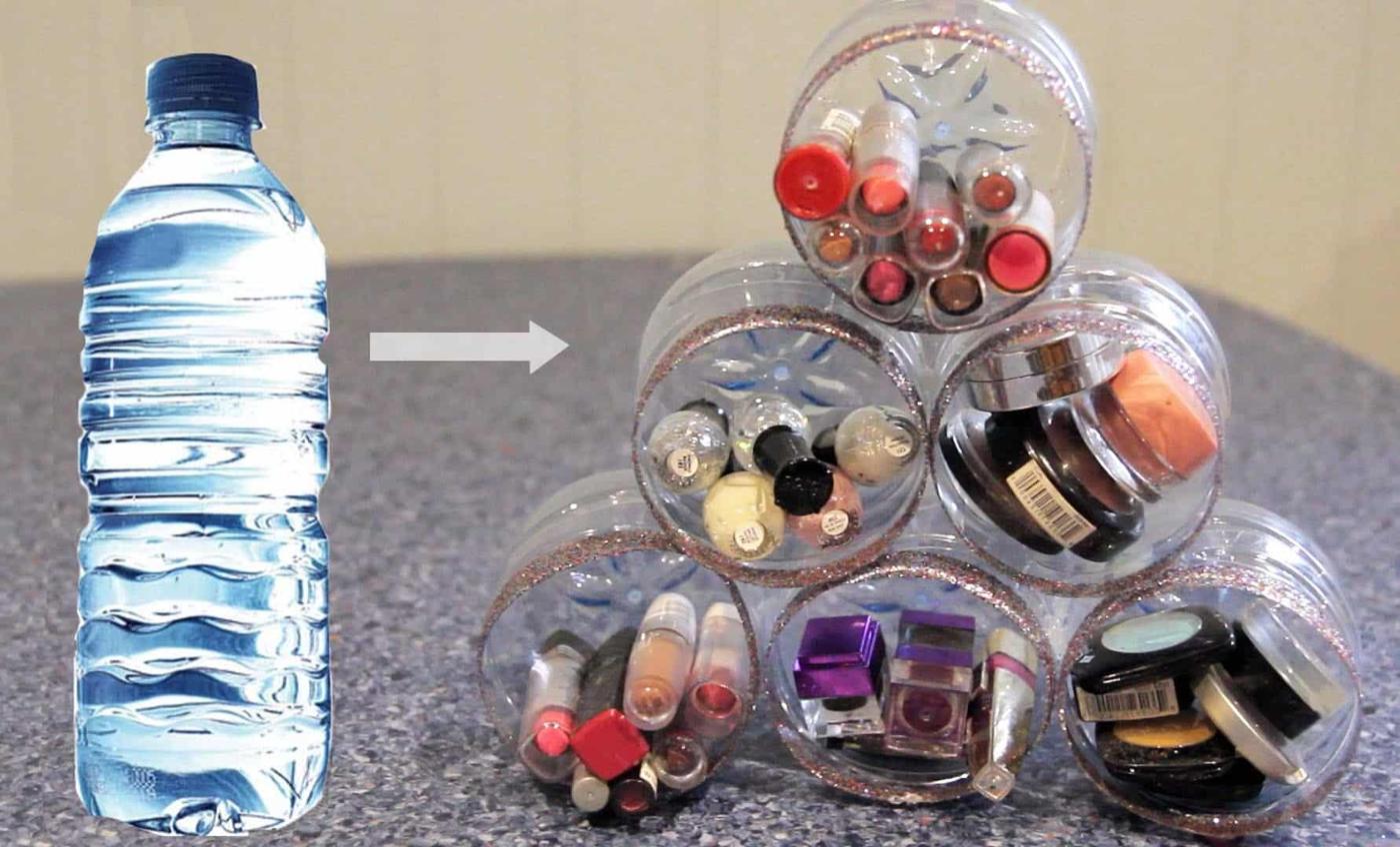 Water bottle bottoms cut into cups with glittered rims, stacked into a pyramid holding lipsticks, nail polish and eyeshadow