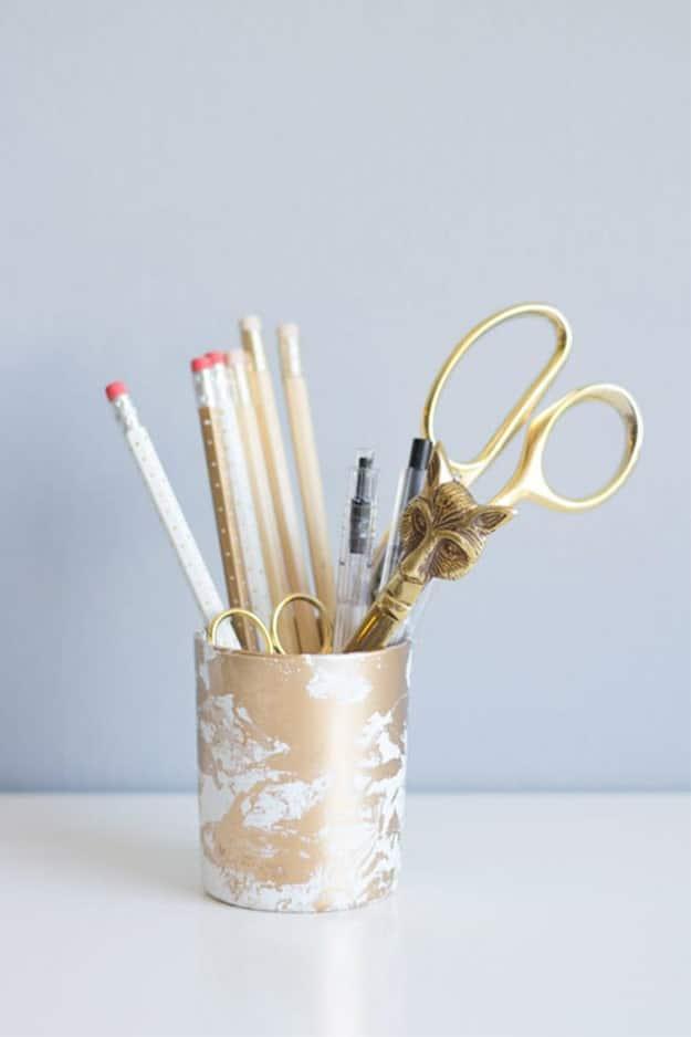 White and gold marbled pencil holders on a desk, created with a simple water-dip clay technique to sell