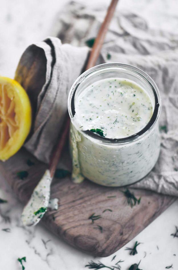 Creamy whole30 ranch dip in a bowl flecked with fresh dill and parsley beside carrot and celery sticks