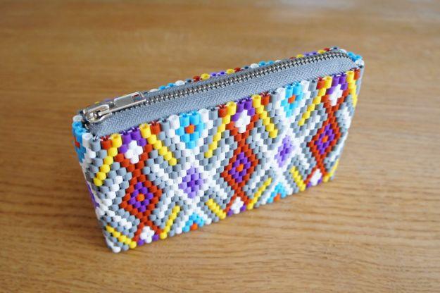 Perler purse, a zipped bead woven pouch in a brown blue and cream diamond kilim pattern on a wooden table