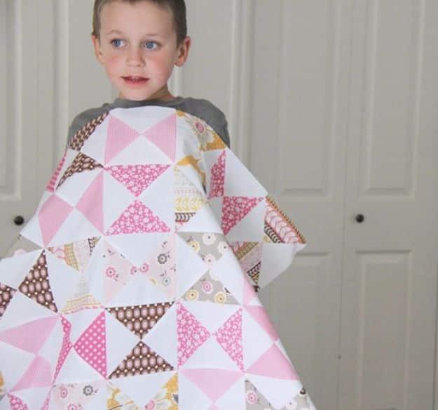 Pink classic hourglass quilt in pink, brown and mustard triangles held up by a young boy in front of a door