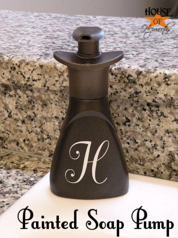 Bronze painted plastic soap pump with a cream monogram letter H on the front standing on a granite kitchen counter