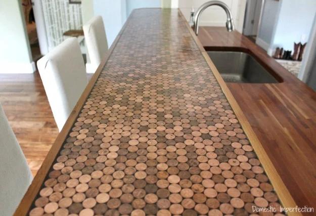 Penny countertop running past a kitchen sink, copper coins under a glossy epoxy surface with a wood edge strip