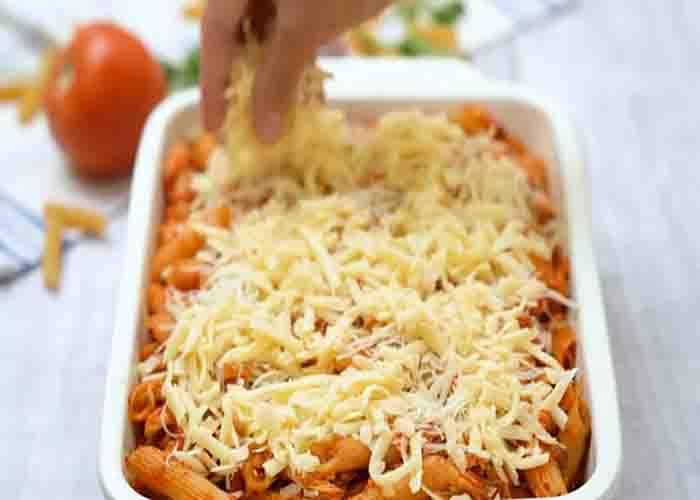 Adding the shredded cheese to the chicken parmesan casserole