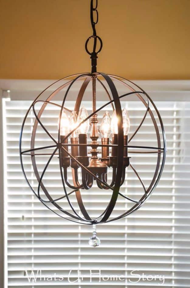 DIY orb chandelier makeover with a bronze wire sphere built around a candle fixture, hanging in front of white blinds
