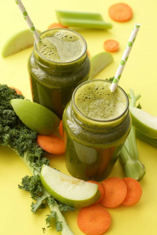 Apple carrot celery and kale juice in two mason jars on yellow with kale, apple and carrot slices around