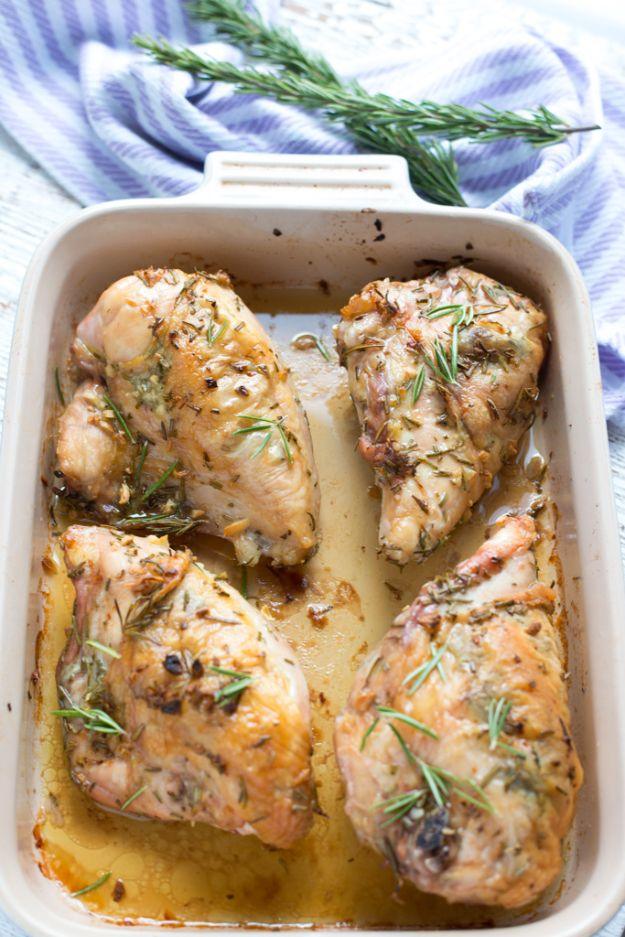 Garlic rosemary roasted split chicken breasts, bone in and skin on, in a cream baking dish with rosemary sprigs