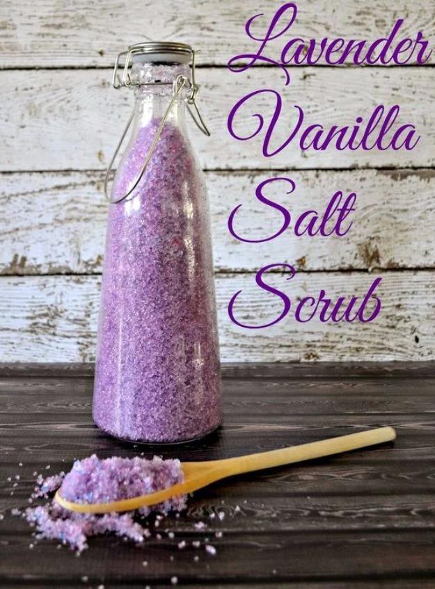 Swing top glass bottle filled with purple lavender vanilla salt scrub with a wooden spoon on grey wood