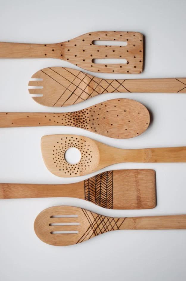 Two wooden spoons with dots and a surname burned into the pale handles, propped in a crock, an Etsy shop idea