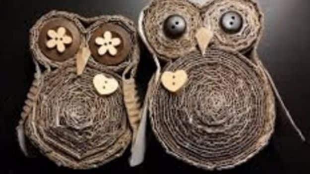 Cardboard craft owls made from coiled corrugated strips with button eyes and feather detail on a black background