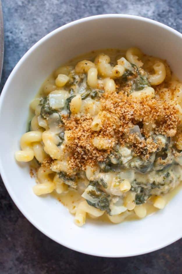 One pot spinach mac and cheese in a white bowl with toasted breadcrumbs and wilted spinach through the pasta