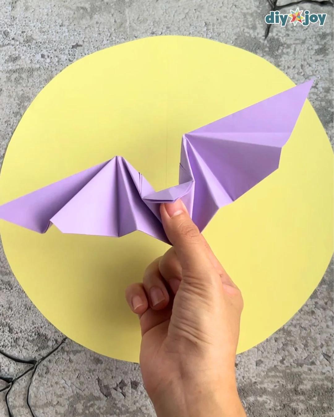 Paper bat craft step 9, shaping the folded wings into their final spread, an easy spooky-season paper craft for kids.